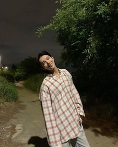 a man standing on a dirt road in front of trees at night with his eyes closed