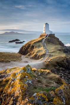 a light house on top of a hill next to the ocean with steps leading up to it