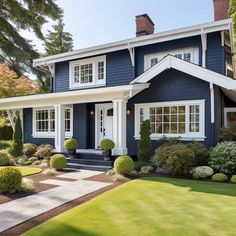 a blue house with white trim and trimmed trees in the front yard is featured on this beautiful sunny day