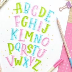 the letters and numbers are drawn with colored crayons on top of paper next to pencils