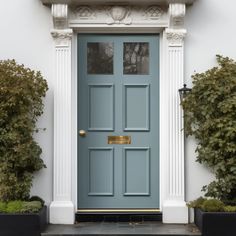 a blue front door with two planters on either side