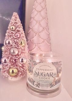 there is a candle next to a pink christmas tree on the shelf in front of it