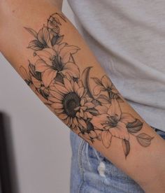 a woman's arm with sunflowers and leaves tattooed on the left arm