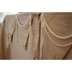 the back of a dress with pearls hanging from it's waist and side panels