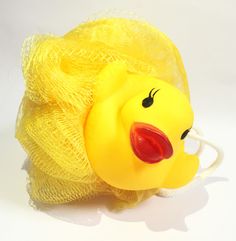 a yellow plastic toy with a red nose and mouth in a mesh bag on a white surface