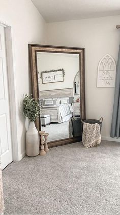 a mirror sitting on top of a wooden dresser next to a bed in a bedroom