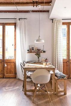 a dining room table and chairs in front of an open door with white drapes