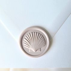 a shell shaped object is mounted on the side of a white envelope with an embellishment