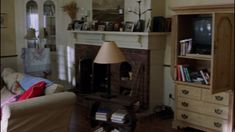 a living room filled with furniture and a fire place next to a book shelf on top of a hard wood floor