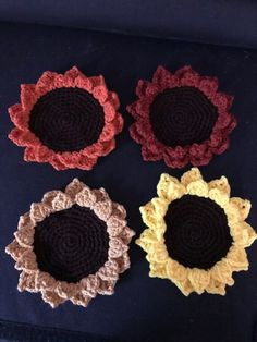 four crocheted flowers sitting on top of a table