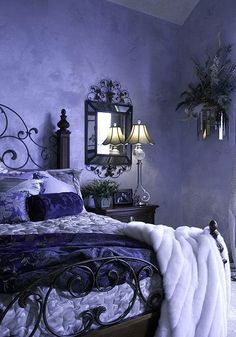 a bedroom with purple walls and white fur on the bed