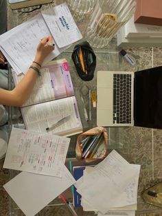 a desk with papers, pens and laptop on it