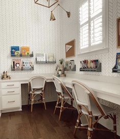 a white desk with chairs and pictures on the wall behind it in a home office