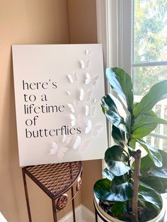 there is a sign that says here's to a life time of butterflies next to a potted plant