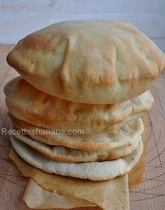 a stack of pita bread sitting on top of a wooden cutting board