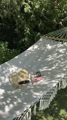 a white hammock sitting on top of a grass covered field next to trees