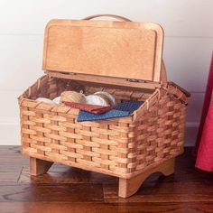 an open suitcase sitting on top of a wooden floor next to a red blanket and pillow