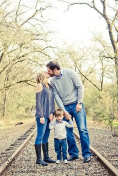 a man, woman and child standing on train tracks