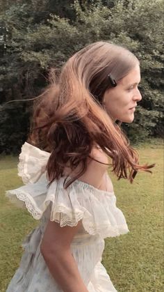 a woman with long hair standing in the grass