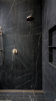 a bathroom with black marble walls and flooring, including a walk - in shower