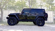 a black jeep is parked in front of some trees