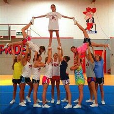 a group of people standing on top of each other in front of a basketball court