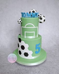 a green cake with soccer balls on top and the number five written in fondant