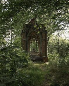 an old building sitting in the middle of a forest with stairs leading up to it