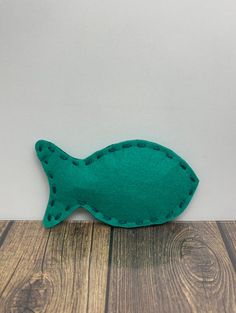 a green felt fish sitting on top of a wooden floor