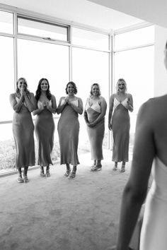 a group of women standing next to each other in front of a large glass window