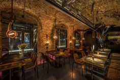 the interior of a restaurant with wooden tables, chairs and lights hanging from the ceiling