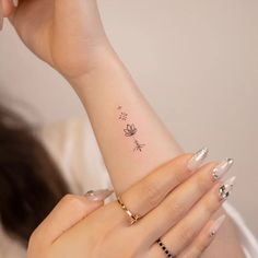 a woman's arm with a small butterfly tattoo on her left wrist and two fingers