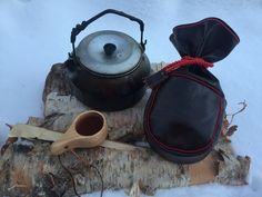 an old tea kettle sitting on top of a tree stump next to a wooden spoon