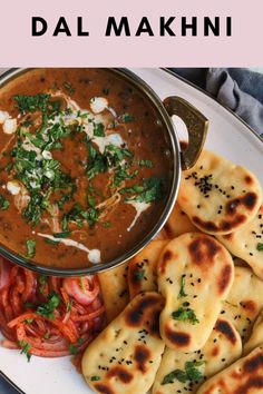 a white plate topped with naan bread next to a bowl of soup and pita bread