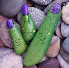 two green vases sitting on top of some rocks next to each other with faces painted on them