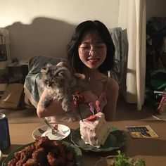 a woman sitting at a table holding a small dog