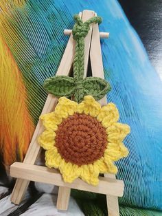 a crocheted sunflower sitting on top of a wooden easel