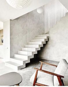 a modern staircase in the middle of a living room with white walls and flooring