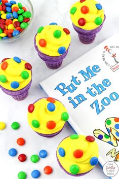 there are cupcakes with candy on the table next to it and a book about put me in the zoo