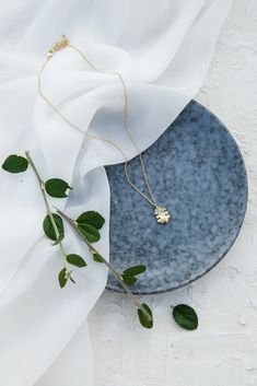 a blue plate sitting on top of a white table cloth next to a green plant