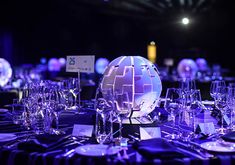 the table is set up for an event with purple lighting and place cards on it