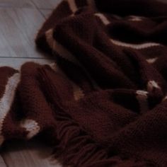 a brown and white blanket laying on top of a wooden floor