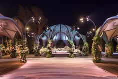 an outdoor wedding venue decorated with flowers and greenery at night in front of a domed structure