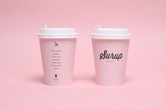 two coffee cups sitting side by side on a pink background