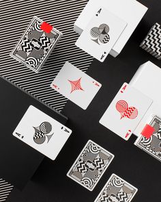 several playing cards are laid out on a black table with white and red designs around them