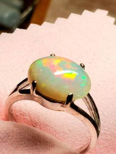 Very colorful 10x14mm  7ct light gray background  opal mounted on a split shank simple design shiny silver ring. Hallmarked Oval Opal Ring, Classic Ethiopian Opal Ring As Gift, Classic Ethiopian Opal Ring In Oval Shape, Hallmarked Oval Ethiopian Opal Rings, Silver Ethiopian Opal Ring, White Ethiopian Opal Ring For Formal Occasions, Formal White Ethiopian Opal Ring, White Oval Ethiopian Opal Rings, White Ethiopian Opal Oval Rings