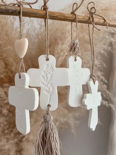 some white crosses hanging from a branch with tassels and hearts attached to them