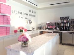 a counter with flowers in a vase on top of it next to a coffee machine