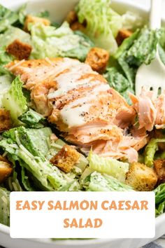 a salad with salmon, lettuce and croutons is shown in a white bowl