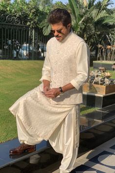 a man in white is sitting on a bench